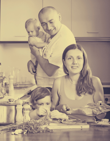 family of four cooking red fish at home kitchenの写真素材