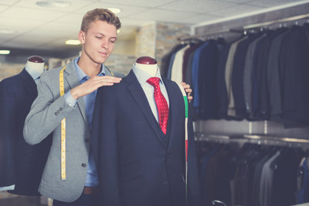 Adult male in shirt measuring business clothes jacket in the store