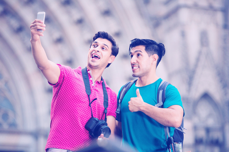 Two  positive smiling friends are walking with baggage and making selfie in Barcelona.の写真素材