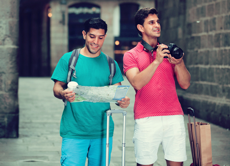 Portrait of two men who are walking with map and photographing on the street in Barcelona.の写真素材