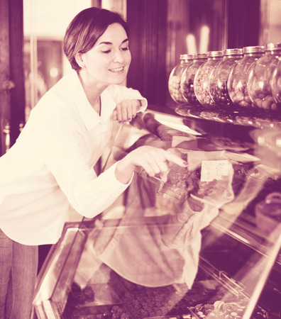 Young female customer examining desserts in confectioneryの写真素材