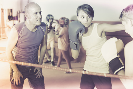 Teenage sportsman at boxing workout with instructor at gymの写真素材