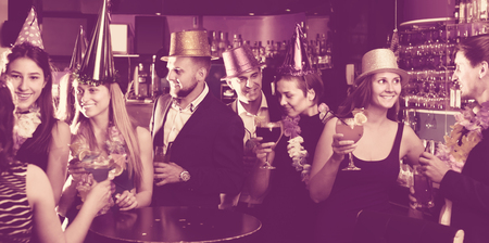 Portrait of young women and men in caps with cocktails in the night clubの写真素材