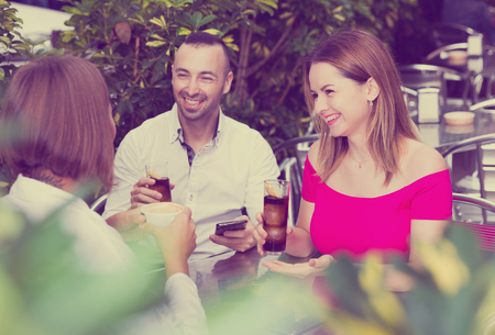 Man with two young women are talking about life and lunching in cafe.の写真素材