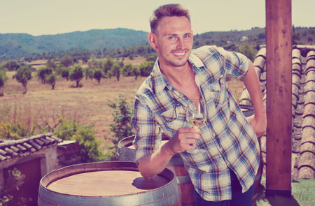 Smiling young man drinking sparkling wine outdoors on terrace with a wine woods