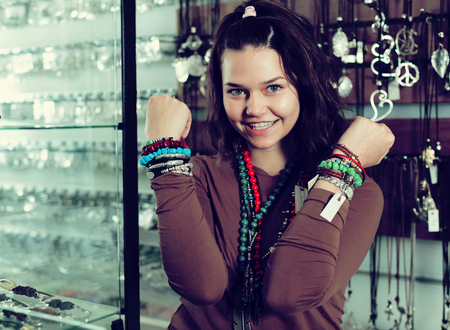 Smiling girl seller offering fashionable bracelets and pendants in the storeの写真素材