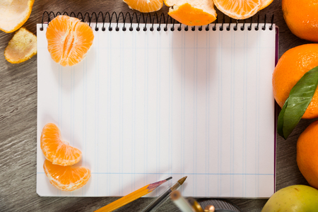 Notebook with writing utensils surrounded by fruitの写真素材