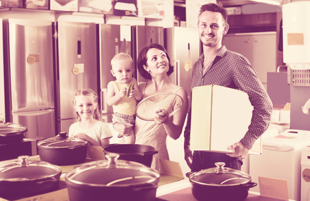 happy family of four buying new cooking pan in household hypermarketの写真素材