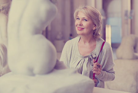 Adult female looking at artwork sculpture in the museum indoorsの写真素材