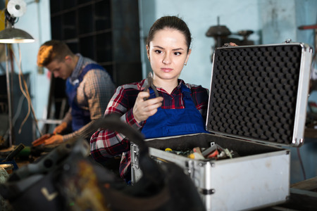 Young woman master is looking tools in box in workplaceの写真素材