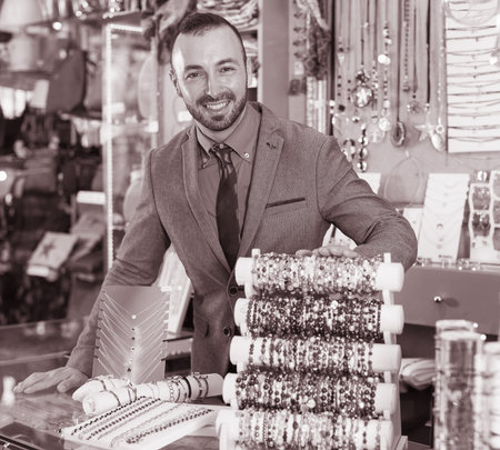portrait of adult man worker selling bracelets in the jewelry store