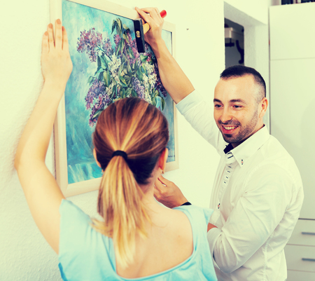 Couple is doing repair and hanging picture on the wall at home.の写真素材