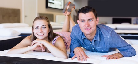 Happy Man and woman choosing mattress in storeの写真素材