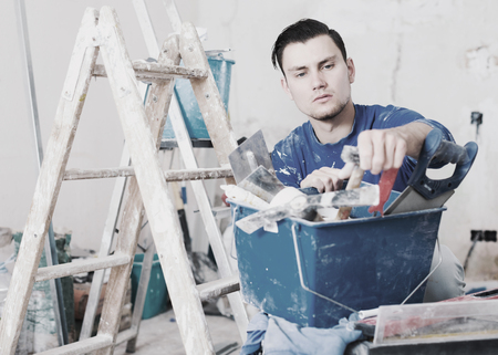 Professionality worker repairing room and looking for necessary tool in toolboxの写真素材