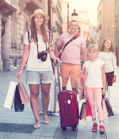 Couple with two kids travelling together on city, walking with baggageの写真素材