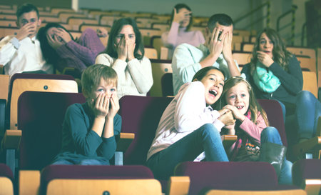 Number of parents and children enjoying scary film in in cinema houseの写真素材