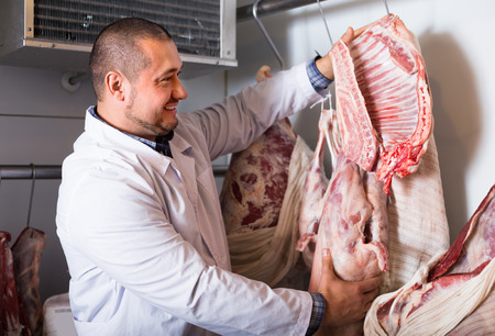 Male shop staff selling kosher meat at counter and smilingの写真素材