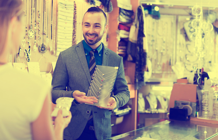 Cheerful male offering to buy fashionable necklace in the shop of jewelryの写真素材