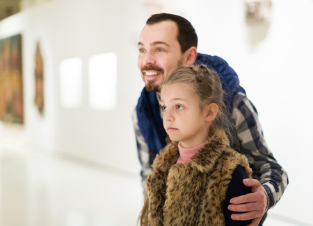 Portrait of smiling father and daughter looking at expositions in museumの写真素材