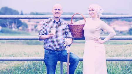 Portrait senior man and young woman chatting and enjoying milk next to metallic fence outdoorsの写真素材