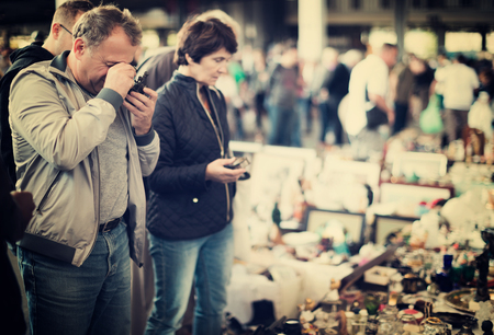 positive couple are visiting market of old things and looking collectible outdoors.の写真素材