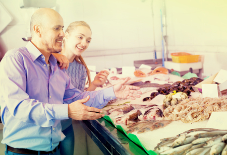Elderly man and young girl choosing seafood in fish store and smiling

の写真素材