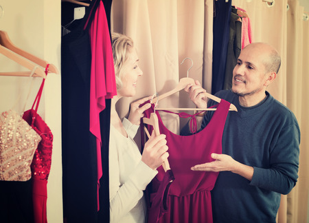 Smiling woman dressing in changeroom of clothing store, husband waitingの写真素材