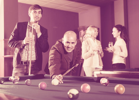 Positive middle class caucasian people having pool game in billiard club
