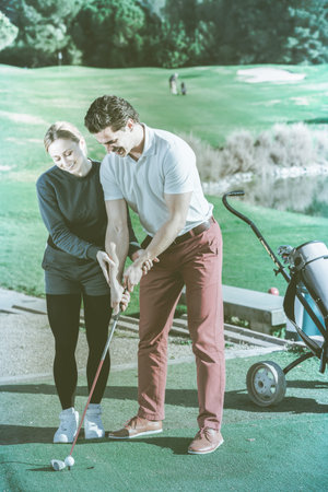 Female golf player shows a man how to put hands when they hit the ballの写真素材