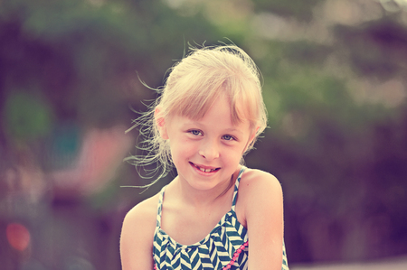 Closeup happy little girl posing on green city landscapeの写真素材