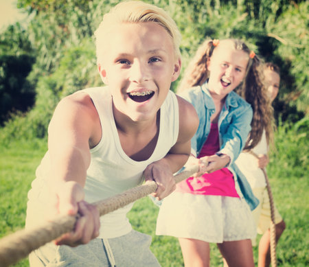 Group of laughing children having fun together outdoors pulling ropeの写真素材