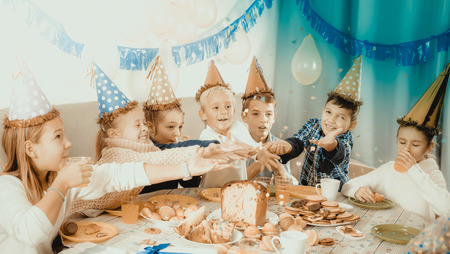 Smiling children enjoying friendâs birthday during festive dinnerの写真素材