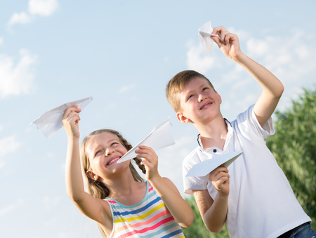 Two smiling kids playing with flying paper planes outdoors
の写真素材