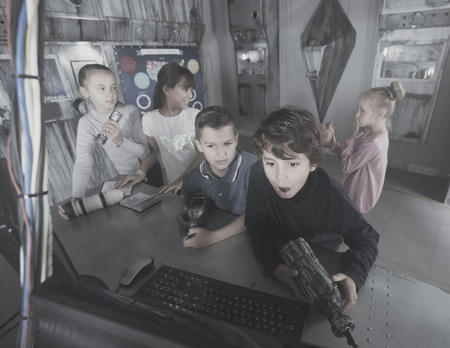 Group of positive children are concentrating on finding a way out of mysterious bunkerの写真素材