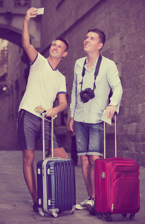 Male couple tourists with luggage doing selfie at street on vacation
 
の写真素材