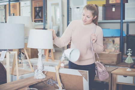 portrait of young woman consumer choosing torchere in furniture shopping roomの写真素材