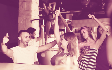 Group of cheerful people clubbing in the night club with drinkの写真素材