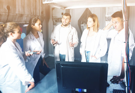 Five positive spanish adults solving conundrums together in quest room in view as abandoned lab
