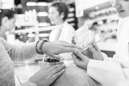 Manicurists giving manicure to female clients at nail salonの写真素材