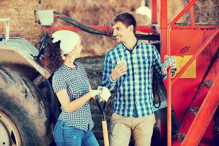 Portrait of two young happy farmers taking a pause and holding the glass with milk の写真素材