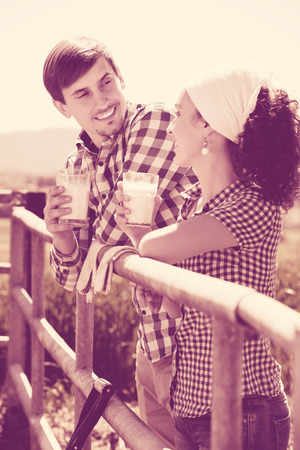 Positive man and woman standing with the fence and drinking milkの写真素材