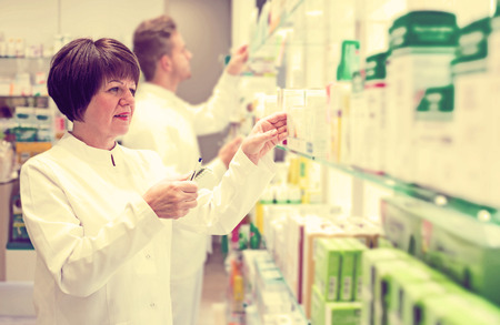 Portrait cheerful pharmacist and pharmacy technician posing in drugstoreの写真素材