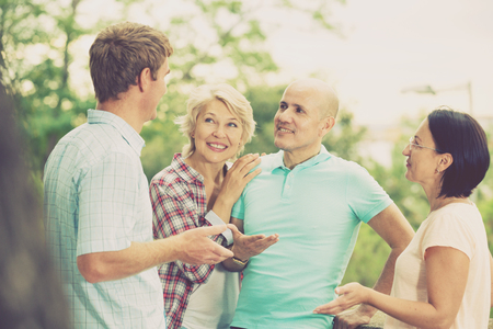 Portrait of mature cheerful males and females talking outdoorsの写真素材
