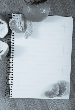 Notebook with empty pages lying amid decoration of tangerines の写真素材