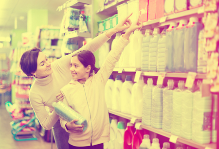 Young woman customer with girl looking for a cleaners for home in a supermarket. Focus on both personsの写真素材