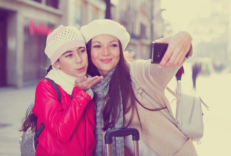 female and child in the historic center taking selfie with baggageの写真素材