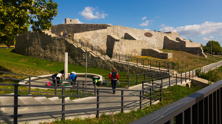 DROBETA TURNU-SEVERIN, ROMANIA - SEPTEMBER 24, 2017: People taking water from source on background with ruins of medieval fortressのeditorial素材