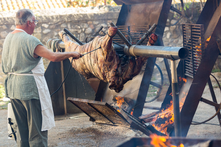 BESALU, SPAIN - SEPTEMBER 02, 2017: Chef cooking on fire whole bull carcass for guests on Medieval Fiestaのeditorial素材