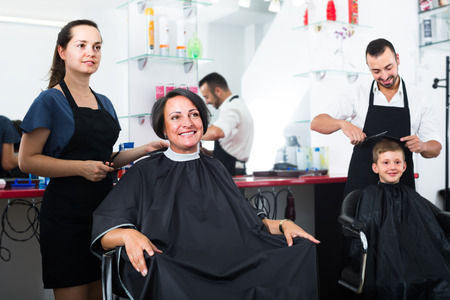 smiling woman 40s getting haircut by female hairdresser in salonの写真素材
