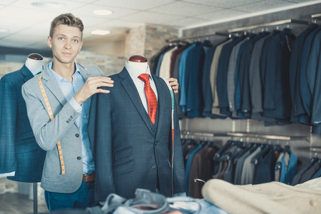 Portrait of man seller measuring business style jacket in the shopの写真素材